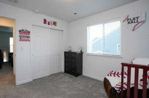Bedroom featuring carpet flooring, baseboards, visible vents, and a closet