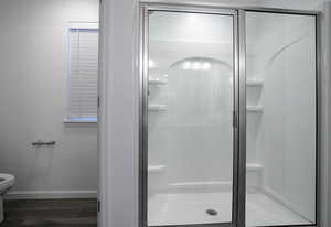 Full bathroom with a shower stall, toilet, baseboards, and wood finished floors