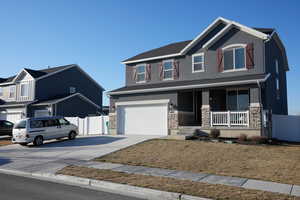 Craftsman-style home with fence, concrete driveway, covered porch, stucco siding, and stone siding