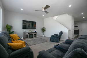 Carpeted living room featuring stairs, recessed lighting, baseboards, and a ceiling fan