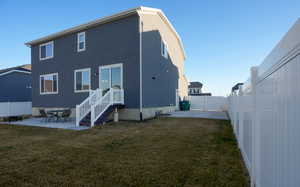 Back of house featuring stucco siding, a gate, a fenced backyard, a yard, and a patio area