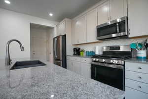 Kitchen featuring a sink, stainless steel appliances, light stone countertops, and backsplash