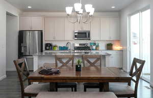 Kitchen with a center island with sink, a sink, dark wood-style floors, appliances with stainless steel finishes, and decorative backsplash
