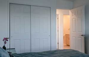 Unfurnished bedroom with a closet, carpet, and ensuite bathroom