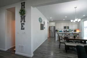 Dining space featuring dark wood finished floors, visible vents, recessed lighting, and an inviting chandelier