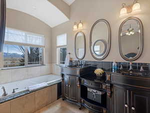 Bathroom featuring a sink, a bath, double vanity, and tile patterned flooring