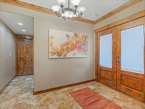 Entryway with visible vents, baseboards, an inviting chandelier, and crown molding