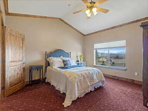 Carpeted bedroom featuring ceiling fan, baseboards, ornamental molding, and vaulted ceiling