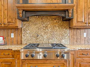 Kitchen featuring tasteful backsplash, brown cabinetry, custom range hood, and stainless steel gas stovetop