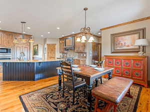 Dining room featuring crown molding, light wood-style flooring, recessed lighting, and arched walkways