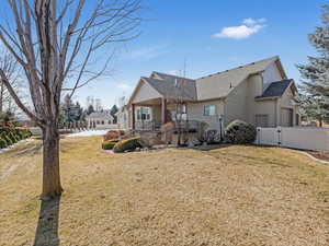 View of front of home with a front lawn, a gate, a garage, and a shingled roof