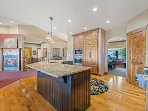 Kitchen featuring a sink, arched walkways, a warm lit fireplace, and built in appliances