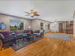 Living area featuring recessed lighting, a ceiling fan, light wood-style floors, and ornamental molding