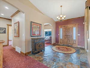 Foyer entrance featuring stone finish flooring, visible vents, arched walkways, and baseboards