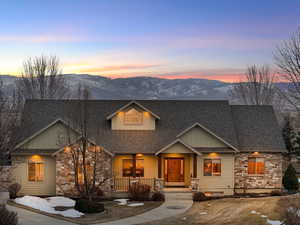 View of front facade featuring a mountain view, stone siding, and a shingled roof