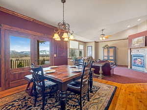 Dining space with a fireplace with flush hearth, ornamental molding, wood finished floors, recessed lighting, and lofted ceiling