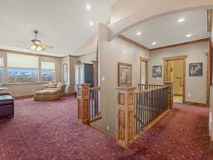 Corridor with baseboards, carpet, ornamental molding, an upstairs landing, and arched walkways