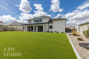 Back of house featuring stucco siding, a lawn, a fenced backyard, and a patio area