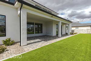 Rear view of house featuring a patio, a lawn, and stucco siding