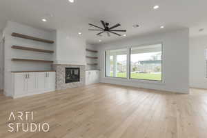 Unfurnished living room featuring a stone fireplace, recessed lighting, a ceiling fan, and light wood-style floors