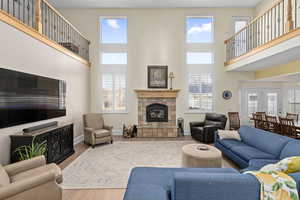 Living room with wood finished floors, baseboards, a towering ceiling, and a tile fireplace