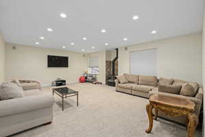 Carpeted living room with recessed lighting, baseboards, and a wood stove