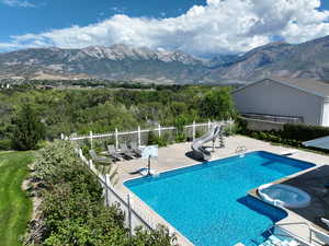 View of swimming pool featuring a mountain view, a water slide, a patio, and fence