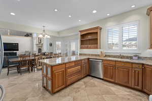 Kitchen with dishwasher, a peninsula, brown cabinetry, and a sink