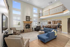 Living area with light wood-type flooring, visible vents, a fireplace, baseboards, and a chandelier