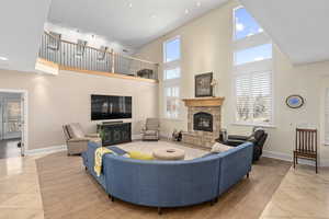 Living area with baseboards, rail lighting, a towering ceiling, a tiled fireplace, and tile patterned floors