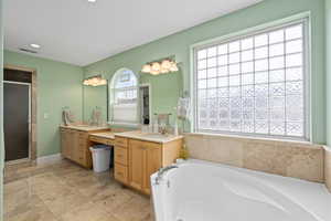 Bathroom with visible vents, baseboards, a garden tub, a stall shower, and vanity