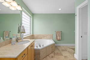 Bathroom with recessed lighting, baseboards, a garden tub, and vanity