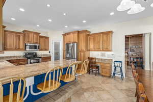 Kitchen featuring a breakfast bar, light stone counters, built in desk, and appliances with stainless steel finishes