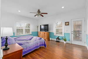 Bedroom featuring multiple windows, wood finished floors, crown molding, and access to exterior