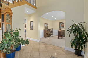 Foyer with crown molding, wainscoting, recessed lighting, arched walkways, and a decorative wall