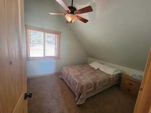 Bedroom with ceiling fan, baseboards, lofted ceiling, and carpet
