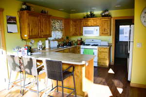 Kitchen featuring white appliances, a peninsula, brown cabinets, and a sink