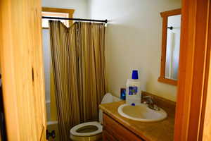 Bathroom featuring shower / bath combination with curtain, toilet, and vanity
