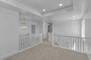 Hallway with an upstairs landing, recessed lighting, light carpet, and baseboards