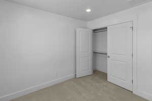 Unfurnished bedroom with visible vents, light colored carpet, baseboards, and a closet