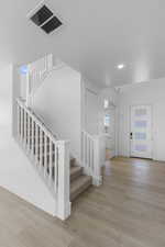 Entryway with stairway, wood finished floors, visible vents, baseboards, and recessed lighting