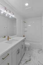 Full bath featuring vanity, a textured ceiling, shower / tub combination, toilet, and marble finish floor