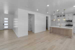 Kitchen featuring light countertops, light wood-style floors, a kitchen island with sink, and stainless steel appliances