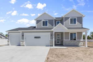 View of front of property featuring fence, concrete driveway, a garage, stone siding, and board and batten siding