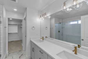 Bathroom with marble finish floor, a shower stall, and a sink