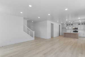 Kitchen with light wood finished floors, a kitchen island with sink, light countertops, appliances with stainless steel finishes, and open floor plan