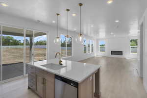 Kitchen with visible vents, light countertops, light wood-type flooring, stainless steel dishwasher, and a sink