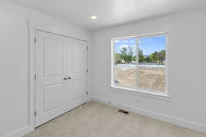 Unfurnished bedroom featuring a closet, visible vents, baseboards, and carpet floors