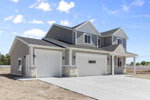 Exterior space with driveway, roof with shingles, stone siding, a garage, and board and batten siding