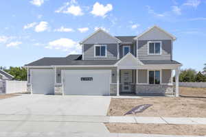 View of front facade featuring board and batten siding, a shingled roof, fence, stone siding, and driveway